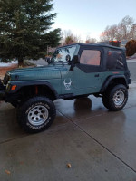 1999 Jeep Wrangler parked outside, featuring a 6-inch lift, custom rims, and winch.