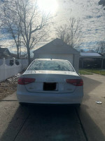White 2013 Audi A4 parked in driveway with a garage in the background on a sunny day
