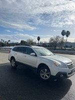 2014 Subaru Outback in white parked outdoors, showcasing its clean condition and all-wheel drive features.