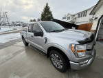 Silver Ford F-150 in excellent condition, equipped with accessories and details, parked on a driveway.