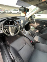 Interior view of a 2010 Mazda 3 with worn seats and dashboard, ready for mechanic repairs.
