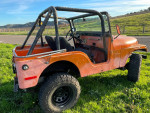1972 Jeep CJ5 with new parts, lifted suspension, and rugged tires parked in a grassy area.