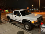 2002 Dodge Ram 2500 Cummins Diesel truck parked at night, showcasing its clean white exterior and quad cab design.