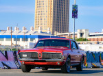 Gorgeous 1968 Mercury Cougar in vibrant red, parked with urban graffiti backdrop, showcasing its classic design.