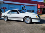 1986 Ford Mustang Foxbody with 306 V8 engine parked in front of a colorful mural.