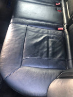Close-up of the black leather interior seat in a 2005 BMW X5 4.8is SUV showing wear and creases.