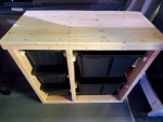 Custom wooden storage unit with black bins inside a 2009 Freightliner Sprinter Van.