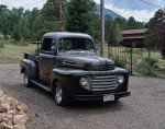 1950 Ford F1 pickup truck with V8 engine and new chrome wheels in scenic outdoor setting.