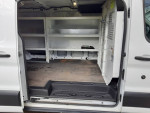 Interior view of a 2016 Ford Transit Cargo Van with shelving, spacious layout and side sliding door.