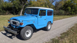 1977 Toyota Landcruiser BJ40 in blue color parked on a gravel road, showcasing its classic design and upgraded features.