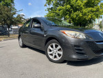 2010 Mazda 3 in excellent condition parked with green trees in background, showing smooth exterior and clean tires.