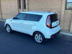2018 Kia Soul hatchback in white, parked in front of a brick building, showcasing its modern design.