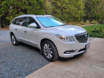 2016 Buick Enclave in excellent condition with white frost exterior and Choccochino interior parked on gravel driveway.