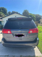 Rear view of a gray 2009 Toyota Sienna LE parked in a sunny residential area.