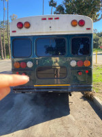Rear view of a 2002 Chevy Bluebird school bus conversion for sale, showing tail lights and unique design.