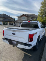 2018 Ford F150 Lariat FX4 in white, showcasing its rear view and black tonneau cover