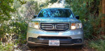 Front view of a silver 2013 Honda Pilot, showcasing its clean exterior and surrounded by trees.