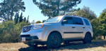 2013 Honda Pilot 4WD parked in a natural setting, highlighting its clean exterior and aluminum skid plate.