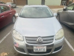 Front view of a 2024 Volkswagen Jetta, silver color, parked with American flag sticker, in good condition.