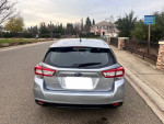Rear view of a silver 2019 Subaru Impreza parked on the street, showcasing its sleek design.