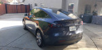 2023 Tesla Model Y Long Range AWD parked in residential area with sleek design and dual motor features.