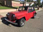 Red 1950 Willys Jeepster Resto Rod with modern upgrades parked on the street.