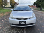 Front view of a 2006 Toyota Prius with low mileage, parked on a clean street with autumn leaves.