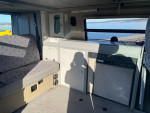Interior view of a 1999 Volkswagen EuroVan camper showcasing seating and kitchen amenities
