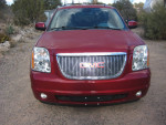 Front view of a 2013 GMC Yukon SLT in red, showcasing its grille and headlights.