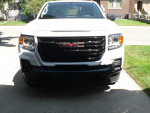 Front view of a white 2022 GMC Canyon Elevation 4WD truck with a bold grille and sleek design.