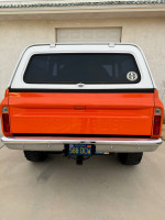 Rear view of a 1971 Chevrolet K5 Blazer in orange with a white hardtop, showcasing classic design and automotive detail.
