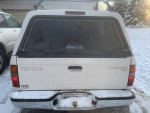 Rear view of a white Toyota Tacoma Xtracab parked in snow, showcasing its clean design and 2WD features.