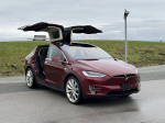 2016 Tesla Model X P90D in red with falcon doors open, showcasing modern design and spacious interior